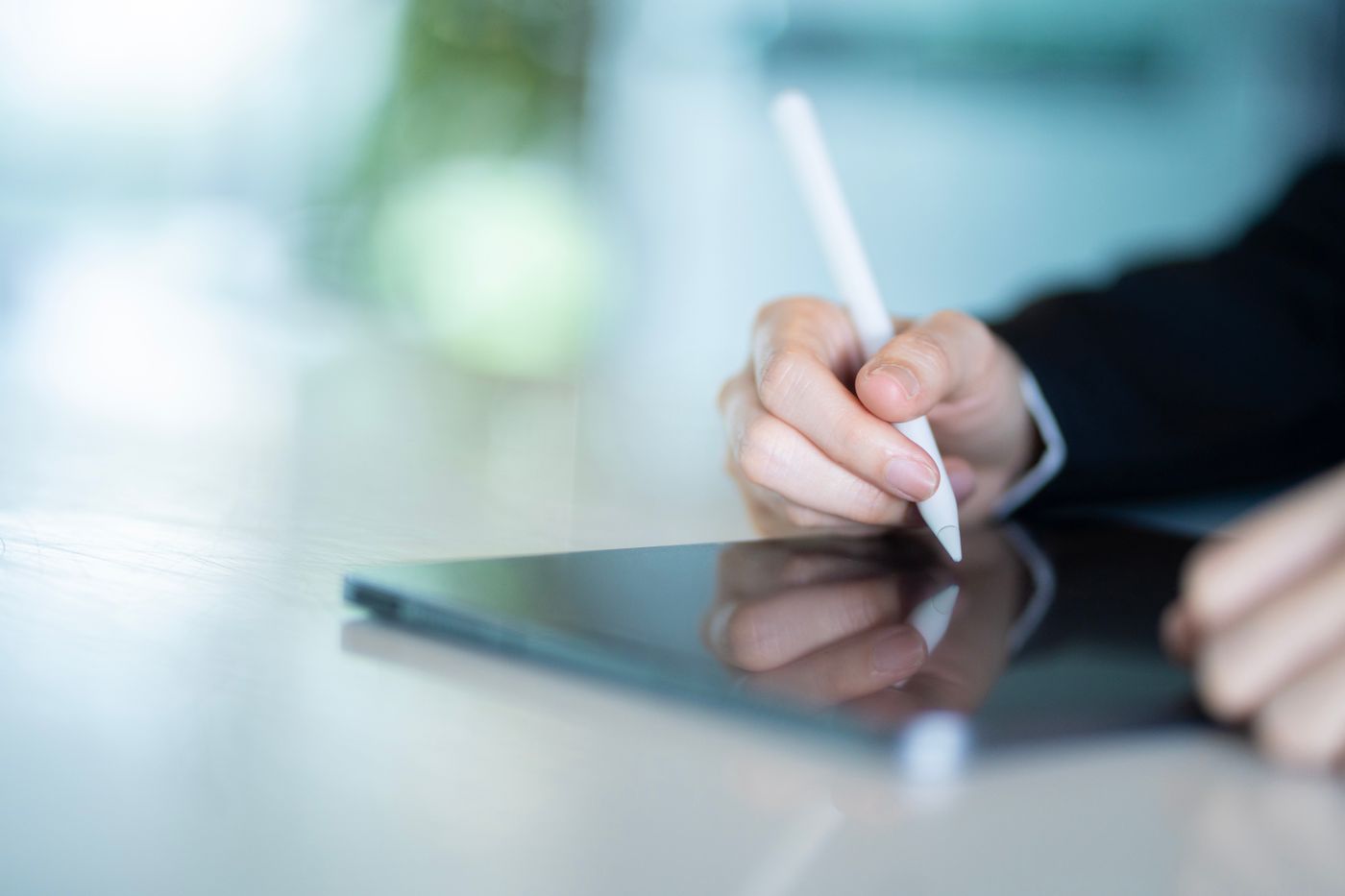 Mână folosind un stylus pe o tabletă, într-un birou modern